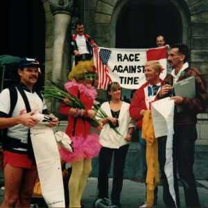 Race Against Time, met vlag Rob van de Gaag en Jos Hellings, daar onder een Amerikaanse activist, Dame Edna (ik), Christina, Piet Driessen en de voorzitter van de HIV vereniging tijdens een demonstratie voor het stadhuis aan de Coolsingel circa 1995.